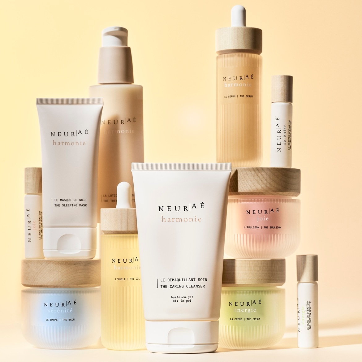 Różnorodność produktów do pielęgnacji skóry NEURAE, w tym balsamy, olejki, emulsje i kremy, prezentowana w eleganckich, minimalistycznych opakowaniach w odcieniach bieli i beżu.