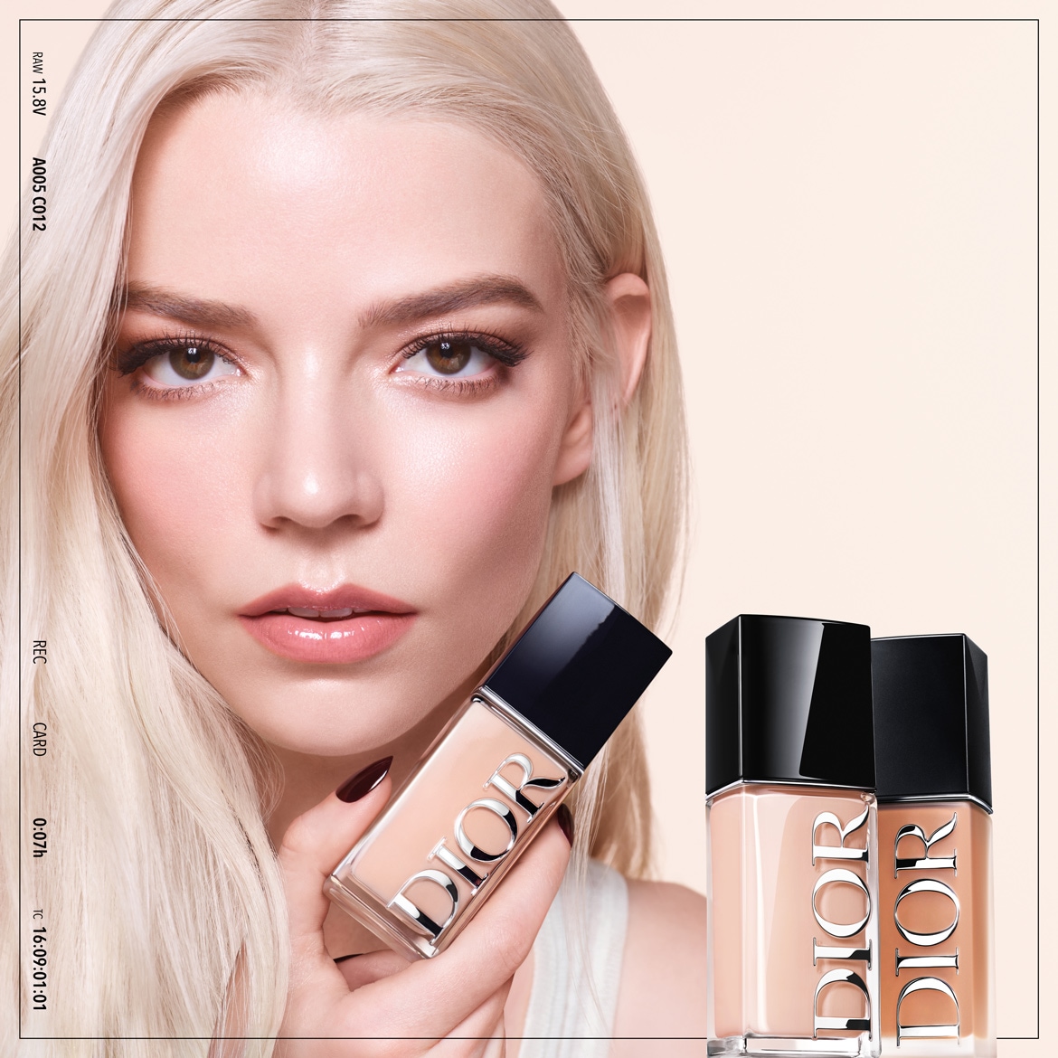 Blondwłosa kobieta trzyma w dłoni podkład Dior w szklanej butelce z czarną zakrętką, obok widoczne są dwie butelki podkładu w różnych odcieniach.