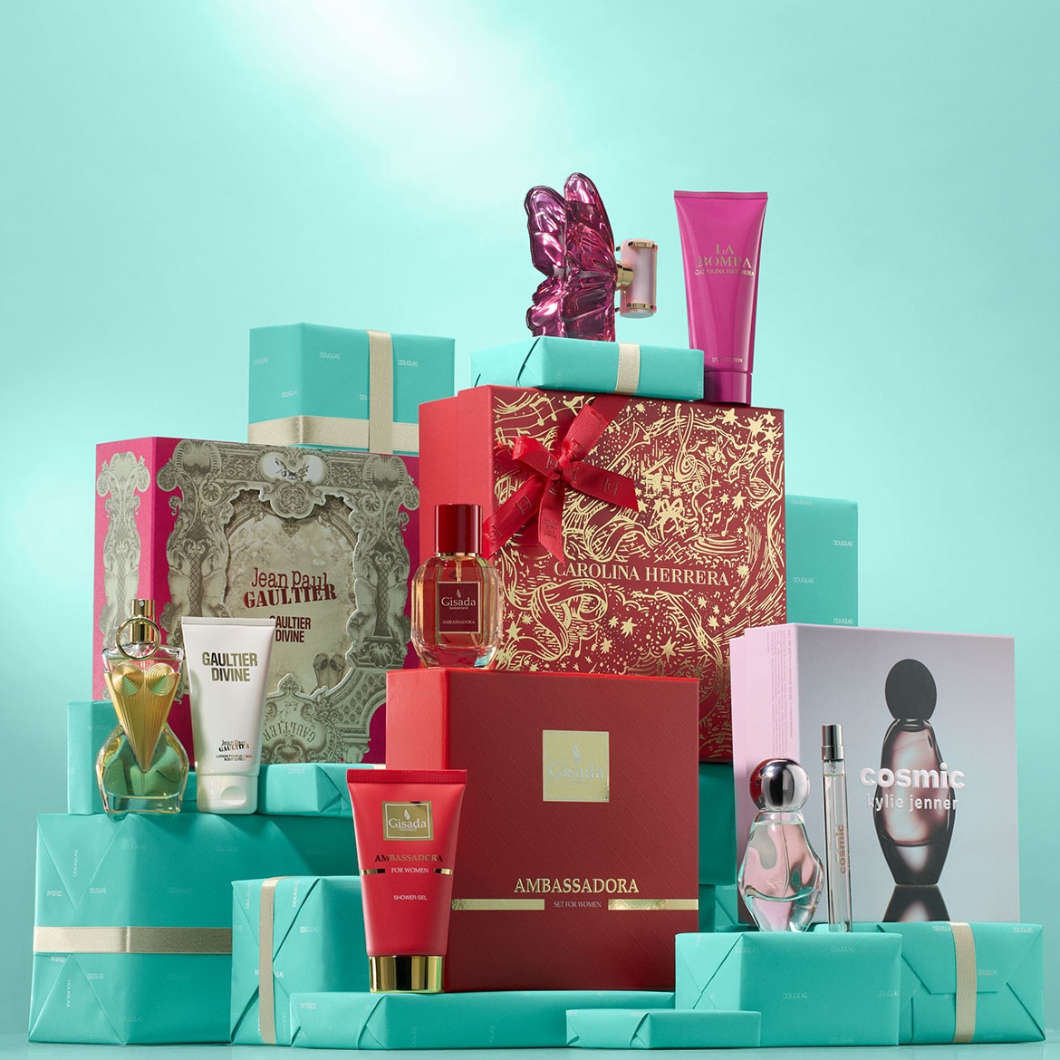 Zestaw prezentowy z perfumami Jean Paul Gaultier Divine, Gisada Ambassadora i Carolina Herrera, zapakowany w kolorowe pudełka i ozdobiony wstążkami.