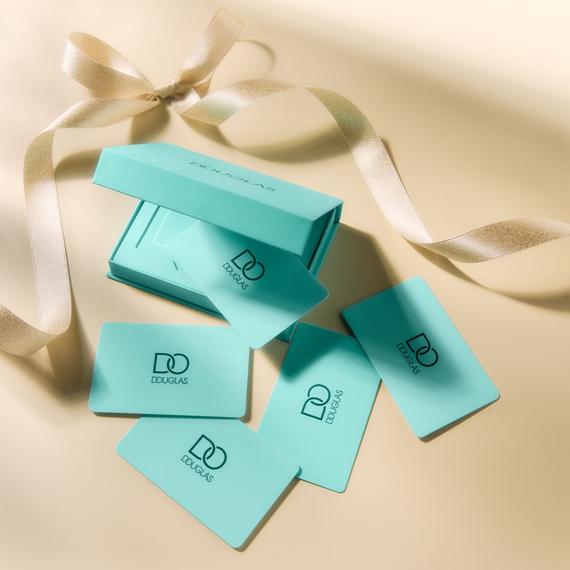 Elegancki zestaw upominkowy Douglas w turkusowym pudełku z kartami podarunkowymi i złotą wstążką, idealny na prezent.