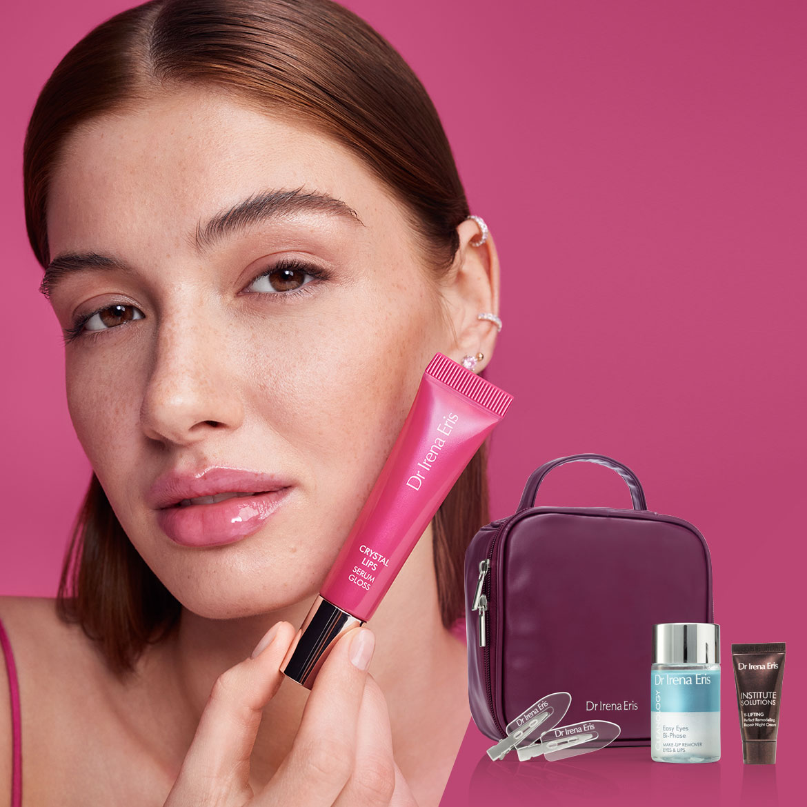 Na różowym tle, kobieta prezentuje błyszczyk do ust Dr Irena Eris Crystal Lips Serum Gloss w różowym opakowaniu, obok kosmetyczka i inne produkty do pielęgnacji.